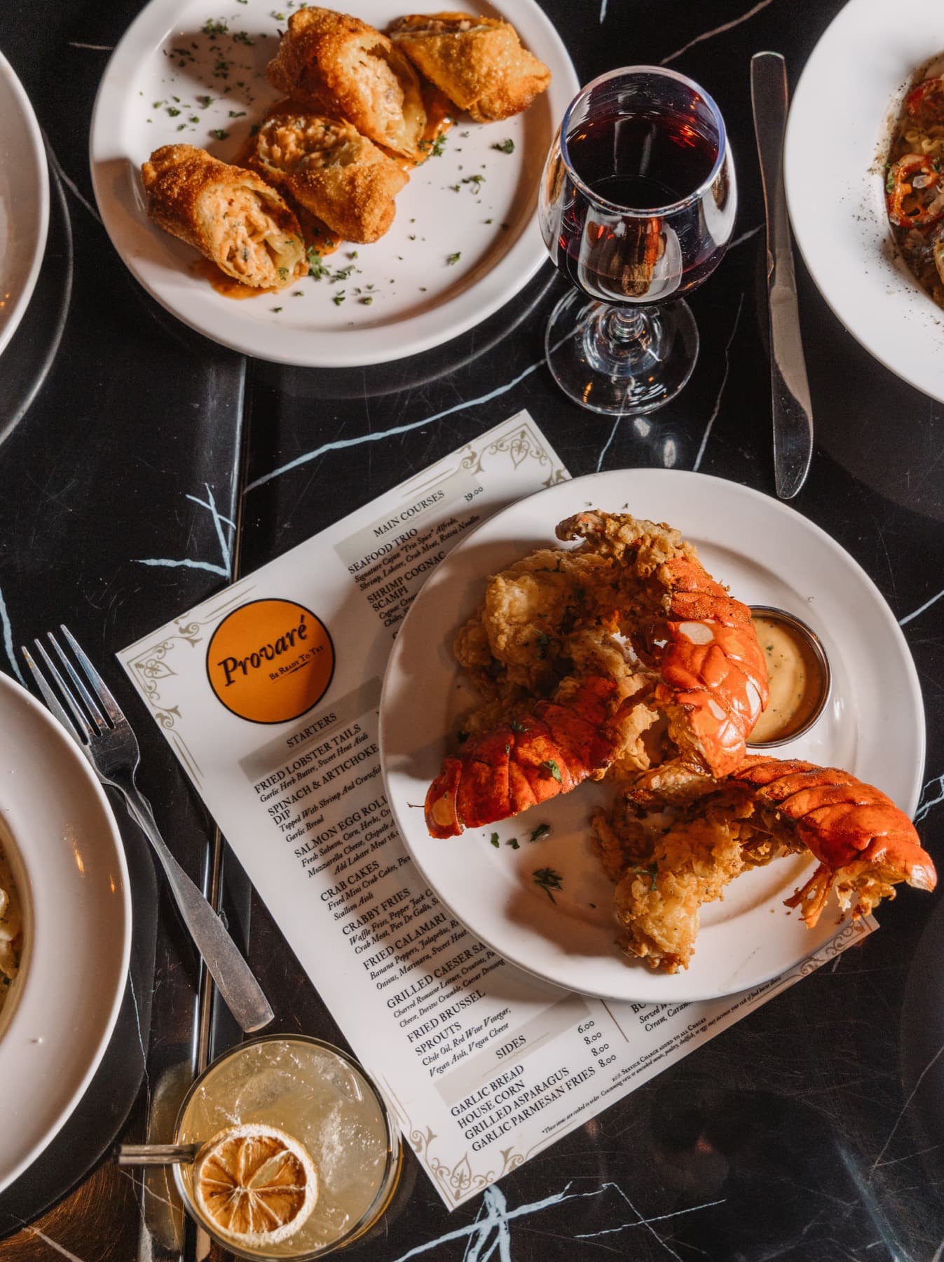 A Provaré table spread with fried lobster, pasta, and wine