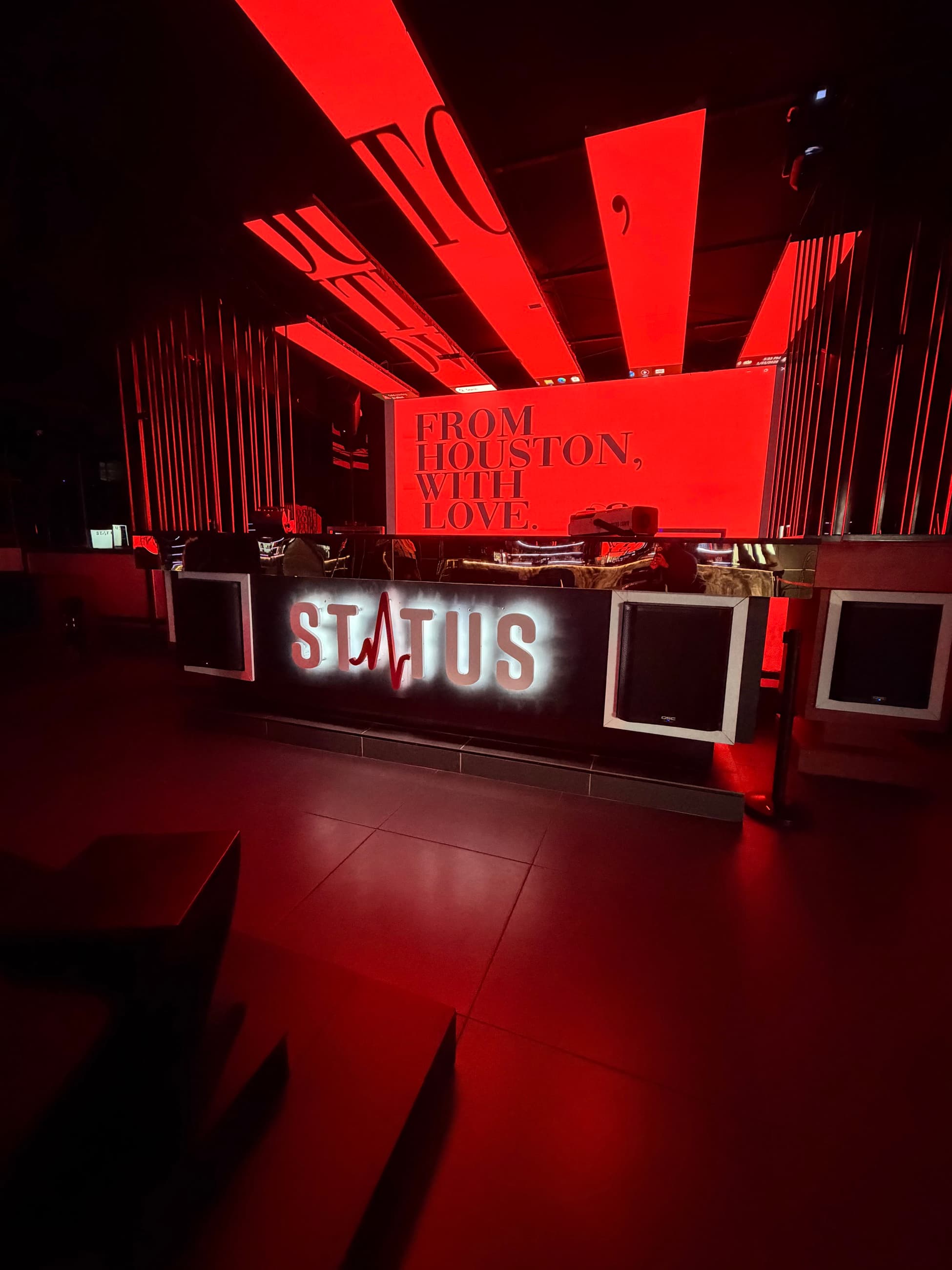 The red-lit DJ booth and Status sign inside Status Club Houston